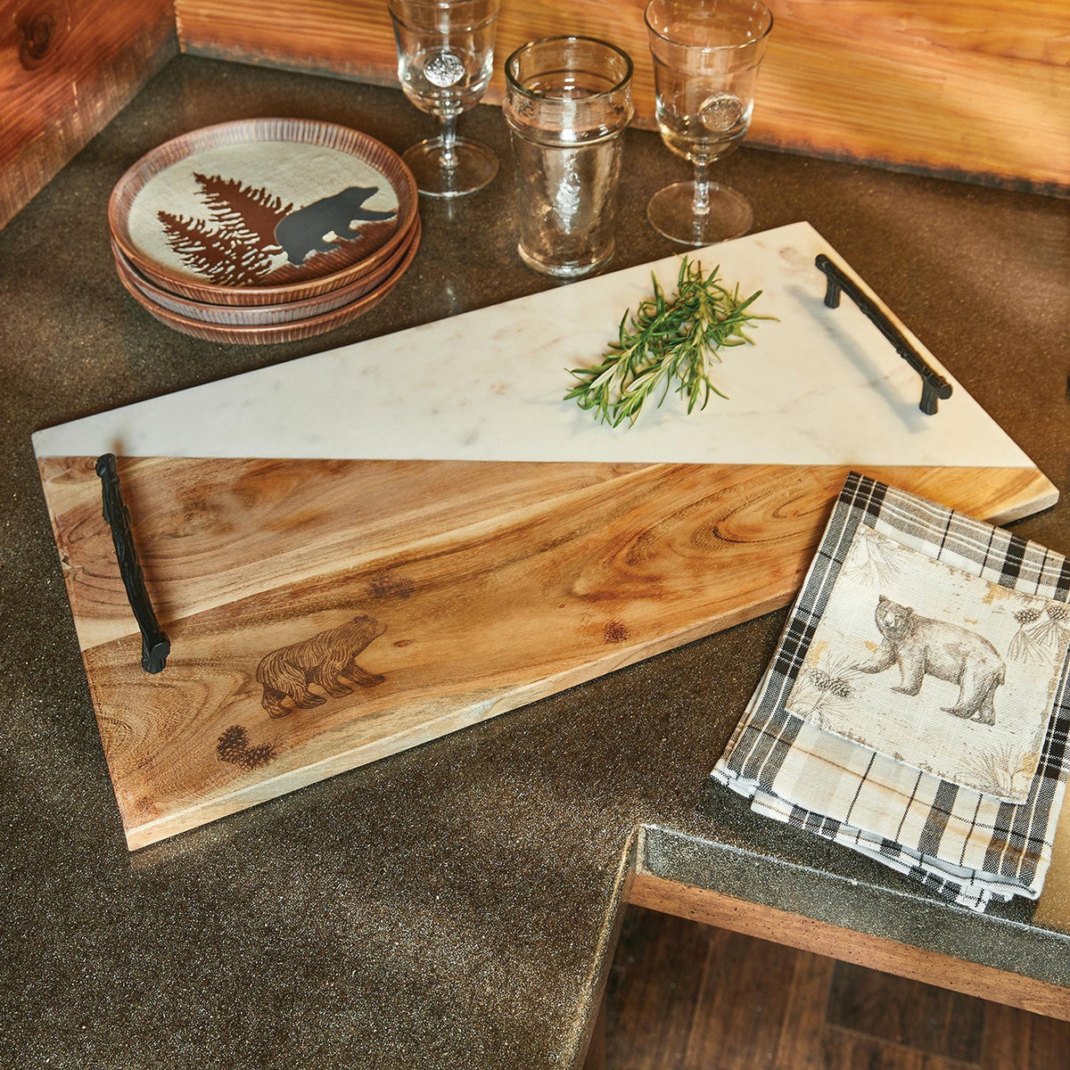 Woodland Bear Cutting Board from Wild Wings features a rustic two-tone design with wood and marble, black handles, and an engraved bear detail.